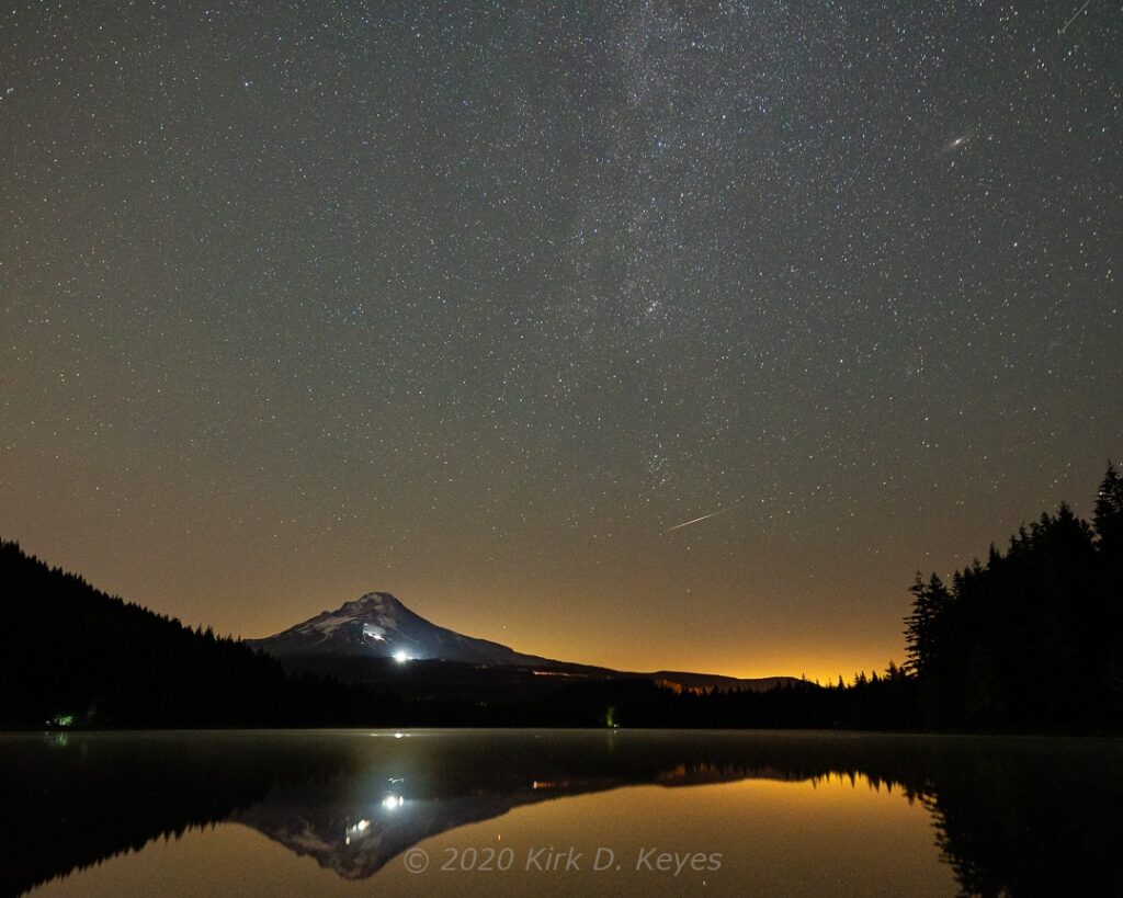 A Perseid meteor passes through the sky over Mt. Hood and Trillium Lake. The Andromeda Galaxy can be seen in the upper right, adding interest along side the Northern Milky Way. 12 Aug 1918. © 2020 Kirk D. Keyes
